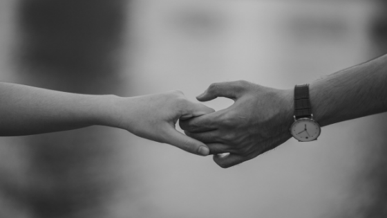 Black and white image of a man and woman releasing a hand hold.