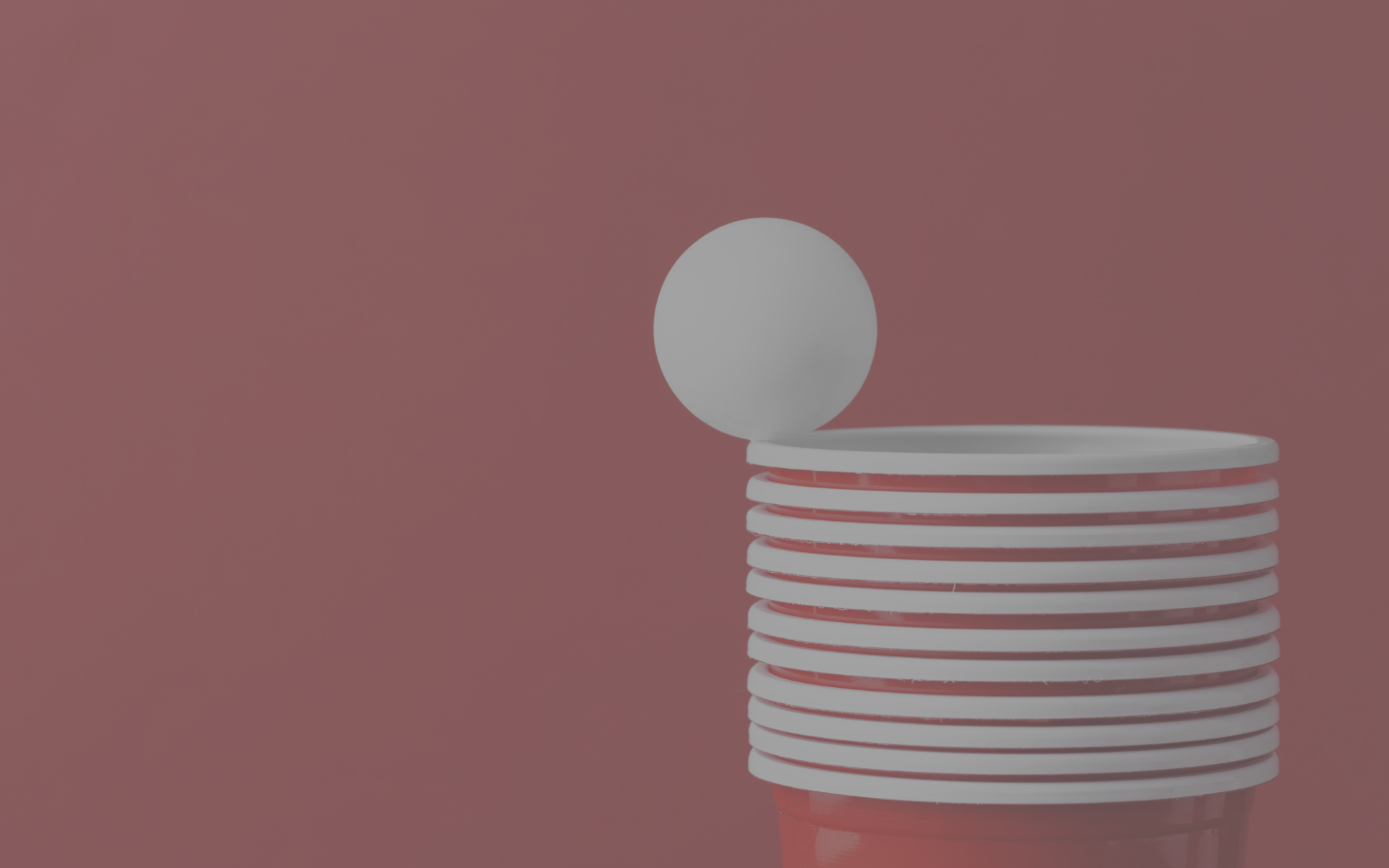A stack of Red Solo Cups with a ping pong ball balancing on the edge.