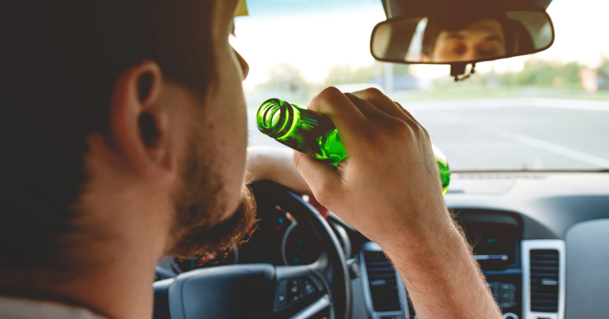 Man drinking beer while driving car