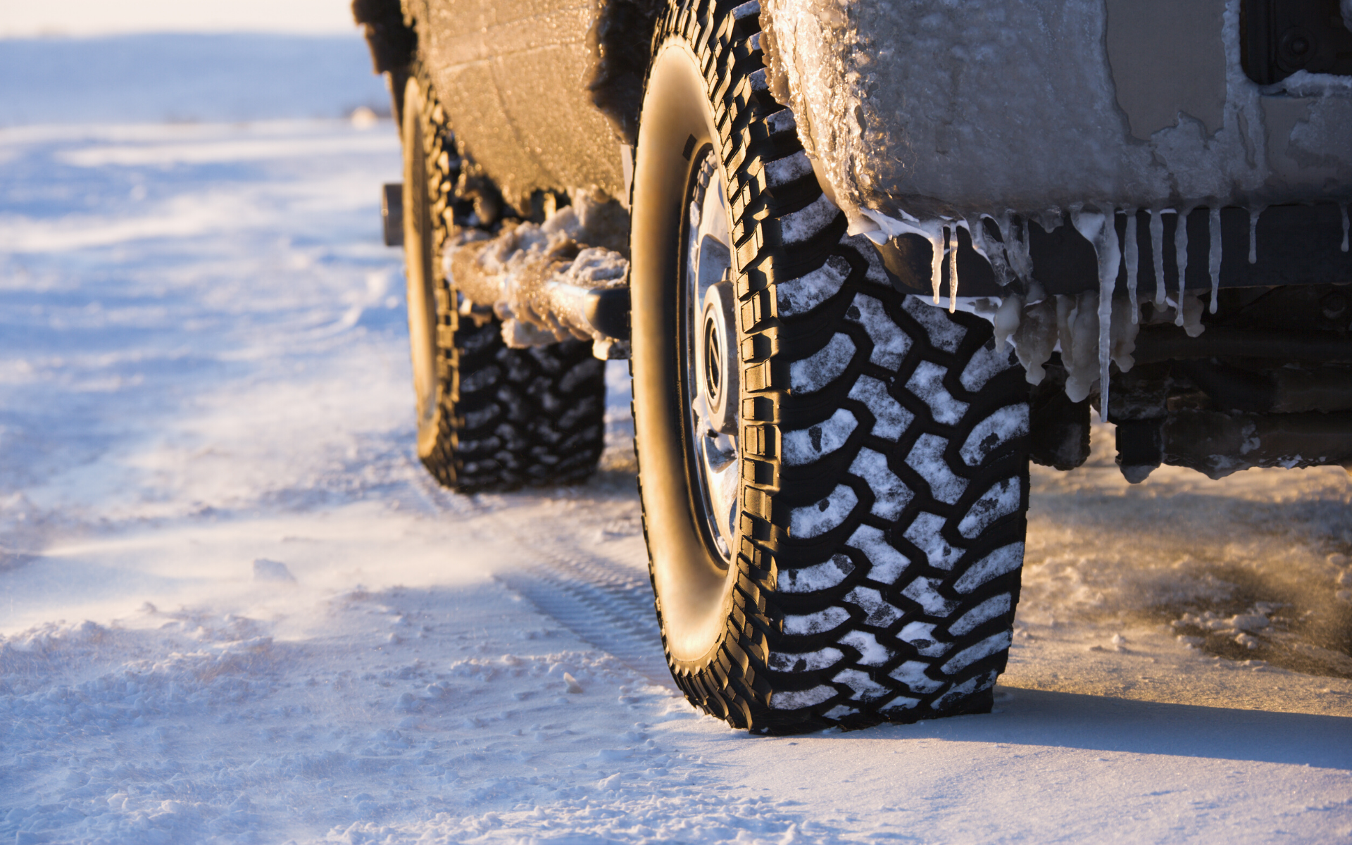 Zoomed in image of a SUV sitting on a snowy and icy road.
