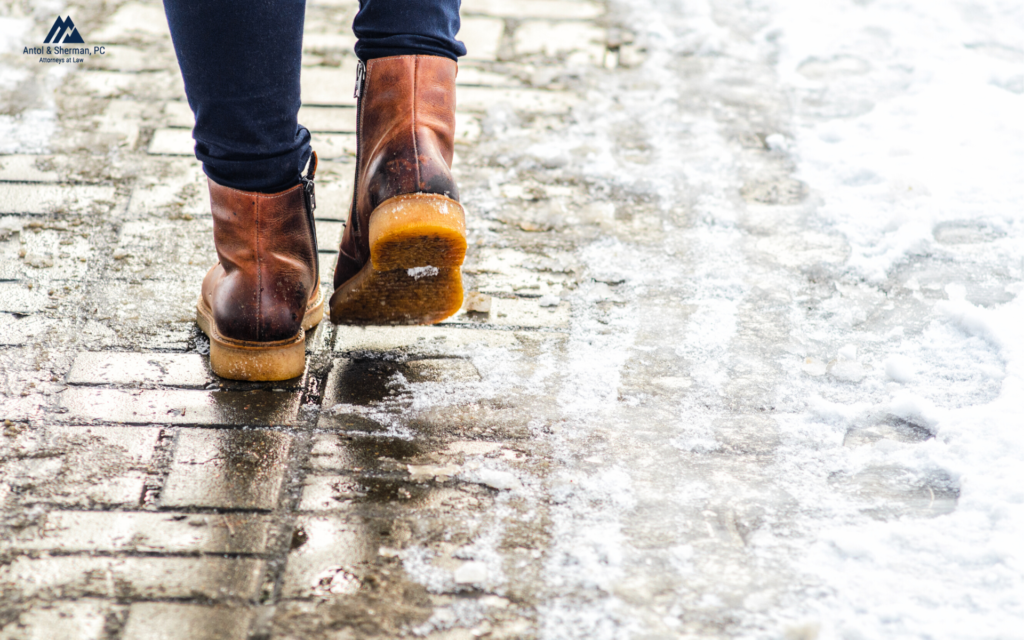 Zoomed in image of a woman walking on an icy sidewalk with boots on.