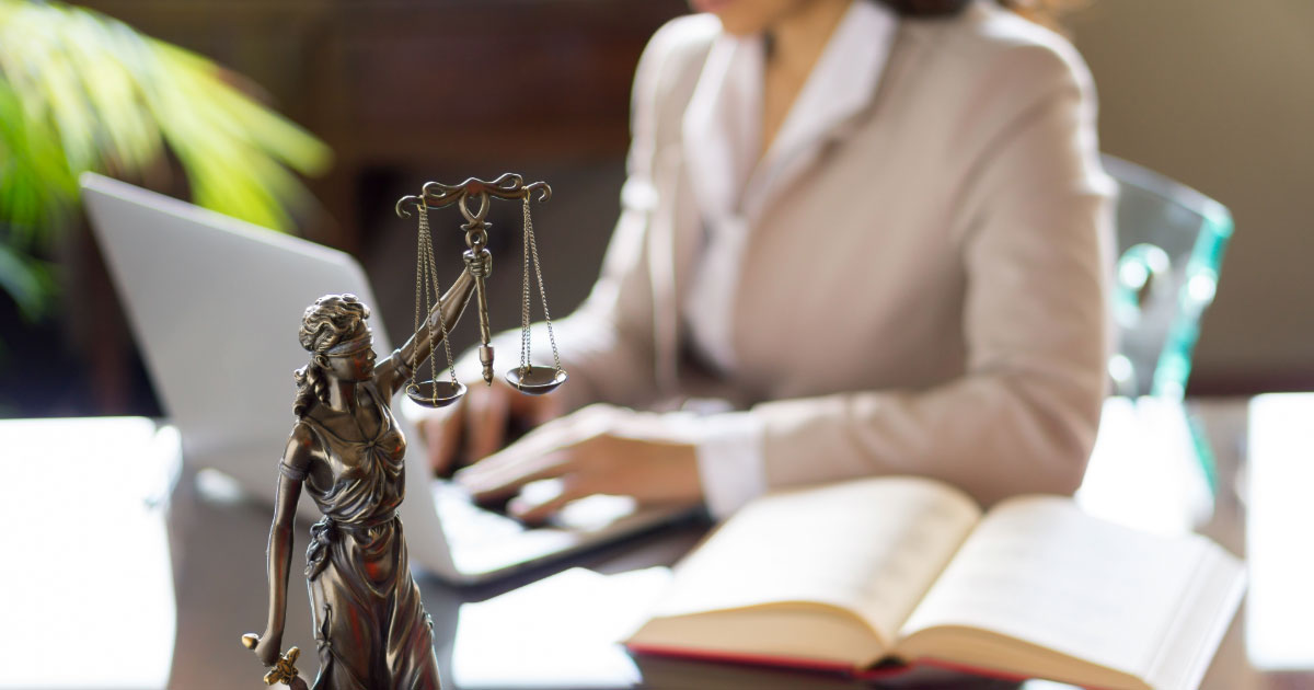 Lawyer working on case with scales of justice on desk