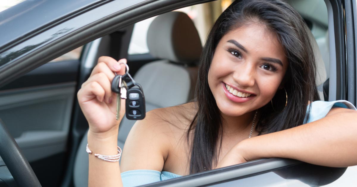 Teen girl dangling car keys out driver's window