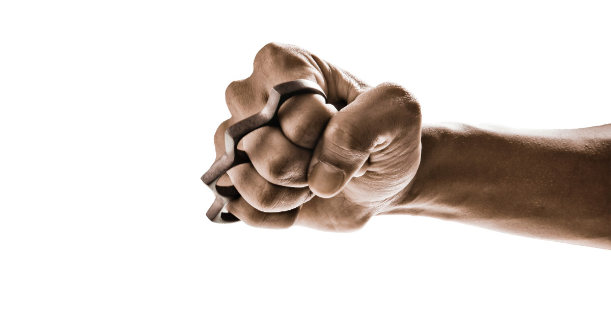 Clenched fist wearing brass knuckles on white background