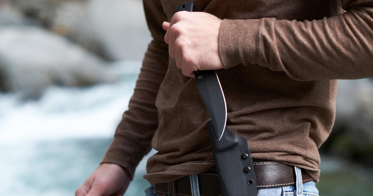 Man taking knife out of his belt scabbard