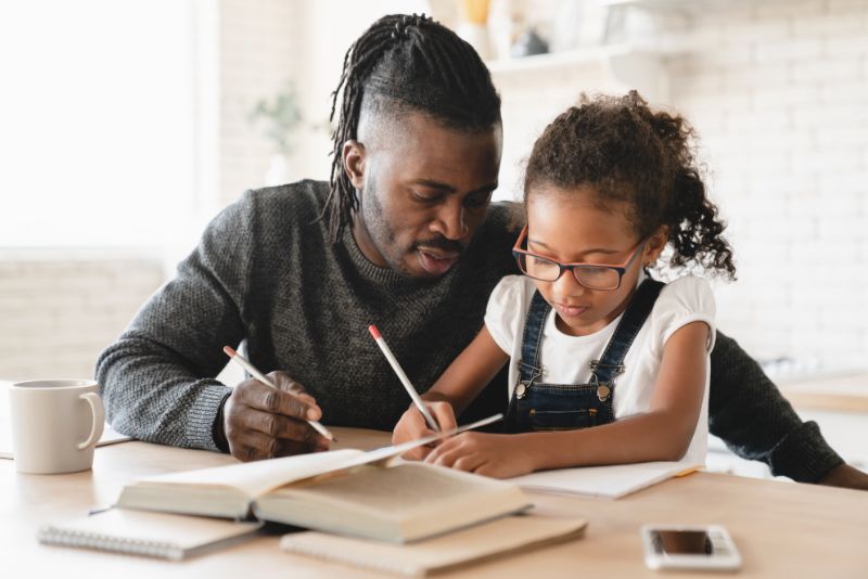 A father helping his daughter with homework.