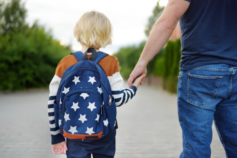A young child walks hand-in-hand with a parent