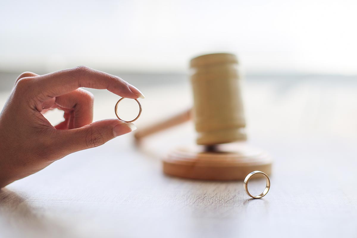 Woman Holding Wedding Ring with Gavel in Background