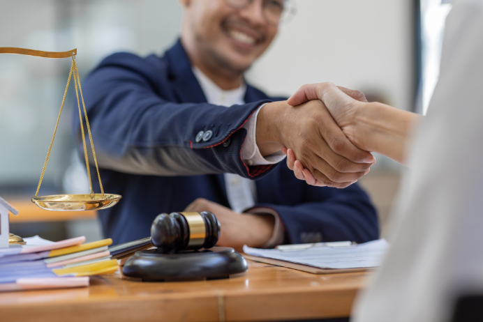 lawyer shaking hands with a person at a desk