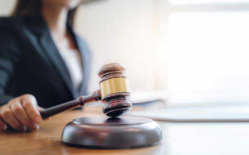 Woman Holding Gavel Sitting at Table