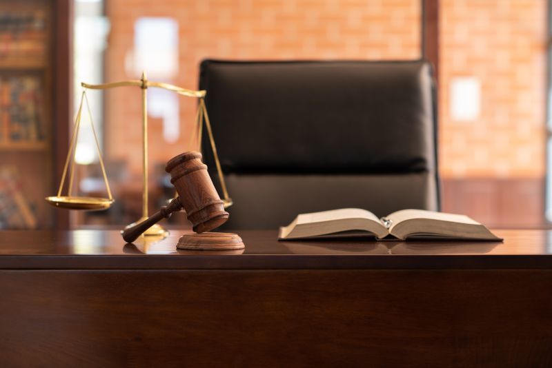 Empty judge's seat with gavel and open book on desk