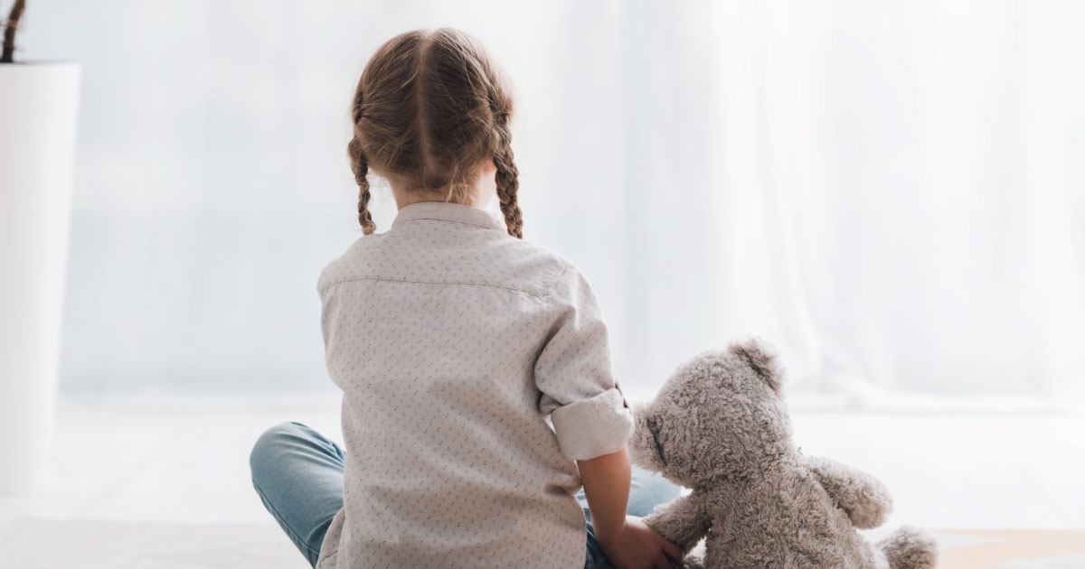 Girl sitting in middle of room with her teddy bear