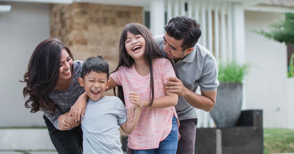 Happy family laughing on front lawn of their home