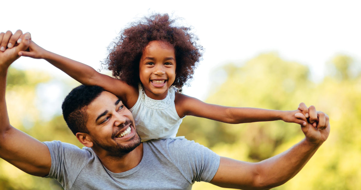 Father carrying daughter on his back in a park