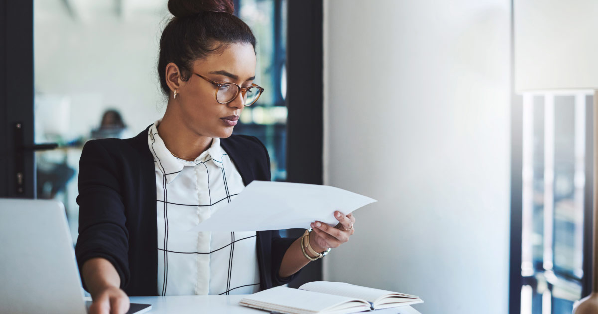 Woman sitting at desk reviewing a piece of paper