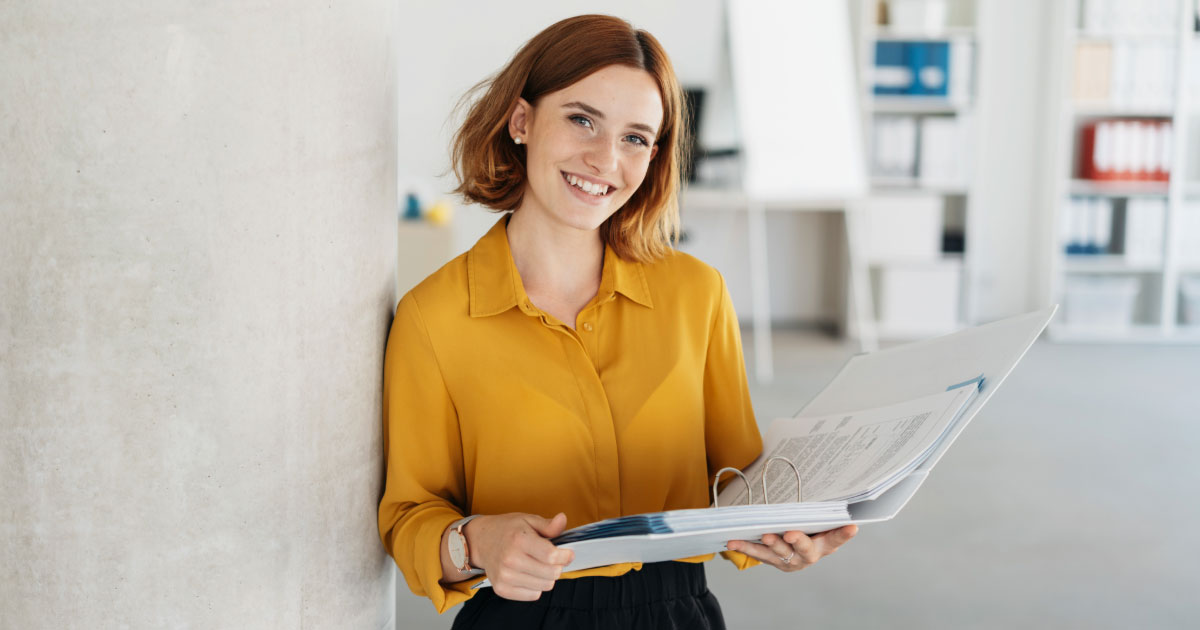 Woman wearing orange shirt holding folder