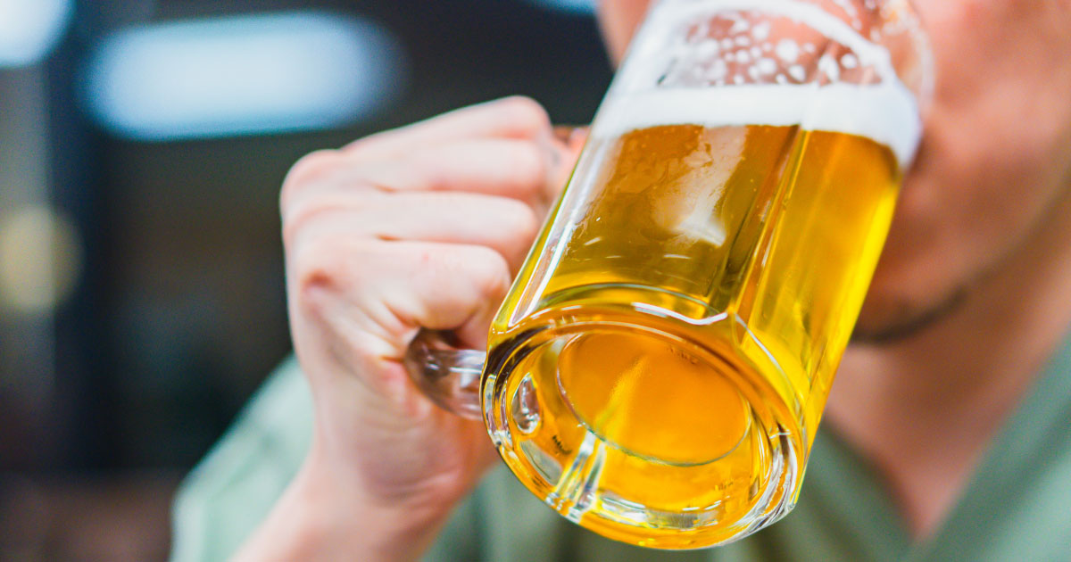 Man drinking large glass of lager beer
