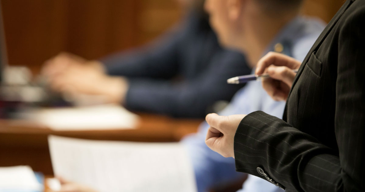 Man sitting in court hearing with lawyer at his side